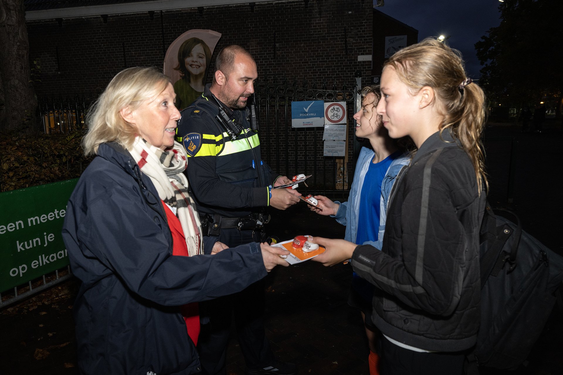 Meisjes die hebben gehockeyd krijgen fietslampjes van politieagent en wethouder Astrid van Eekelen